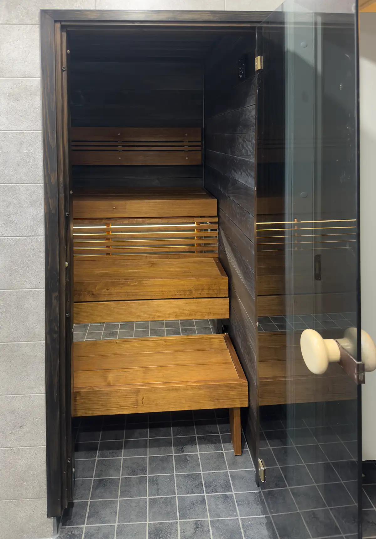 Yksilöllisesti suunniteltu sauna- ja kylpyhuoneremontti, jossa mittatilaustyönä rakennetut lauteet.