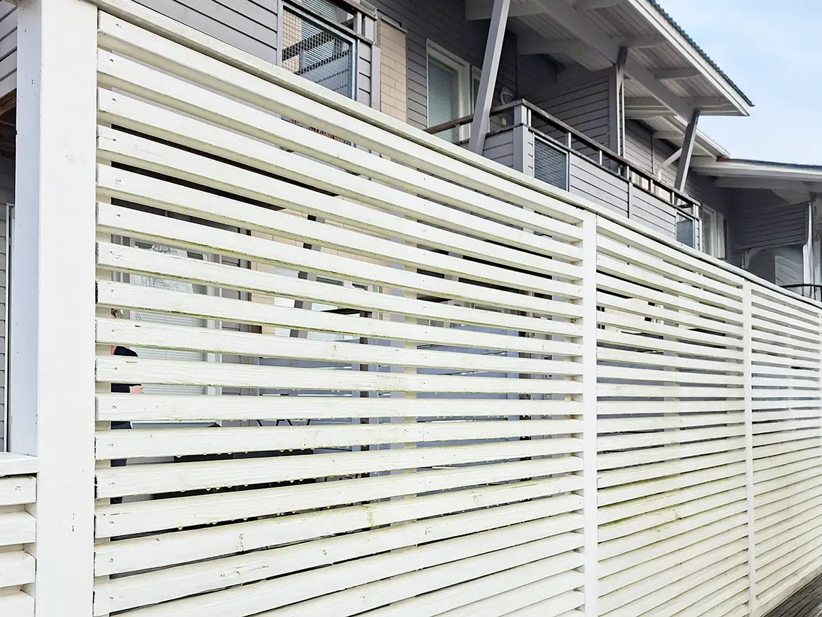 Moderni valkoinen vaaka-aitaelementti puuterassilla asennettuna.