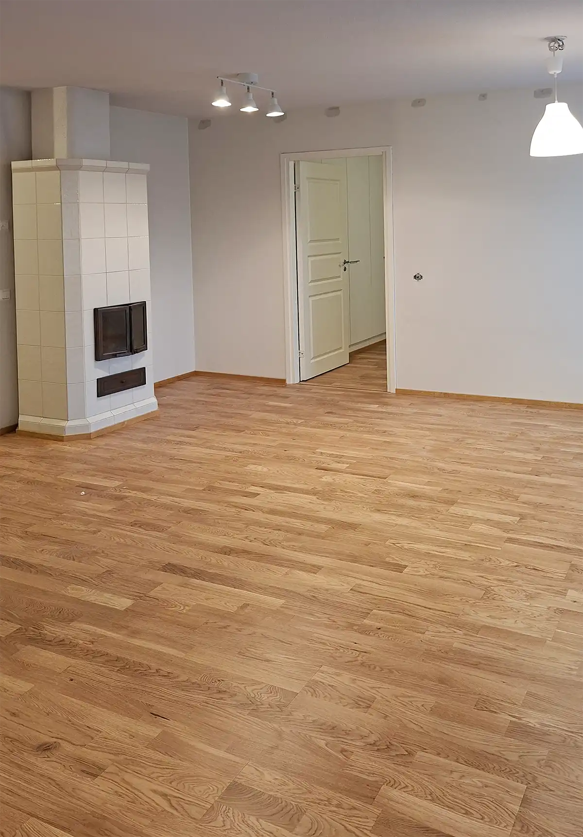 Olohuone saneerauksen jälkeen – uusi parkettilattia ja uudet vaaleat pinnat muodostavat avaran kokonaisuuden, joka sopii yhteen tilassa ennestään olleen takan kanssa.