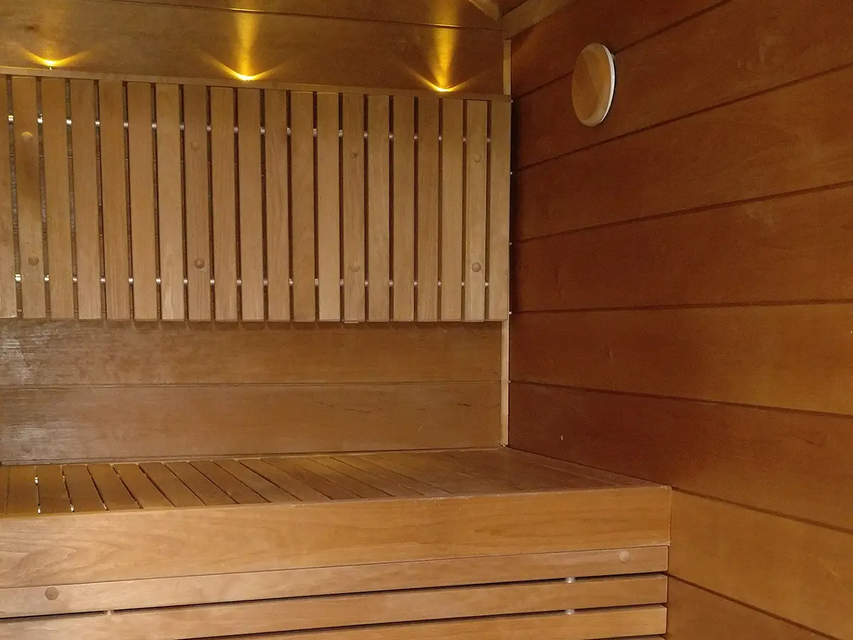 Remontoitu sauna Espoossa, jossa on puupintaiset lauteet, seinäpaneelit ja epäsuora valaisuratkaisu selkänojan yläpuolella.
